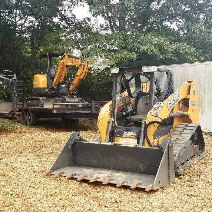 Skid steer and excavator clearing brush on a wooded lot